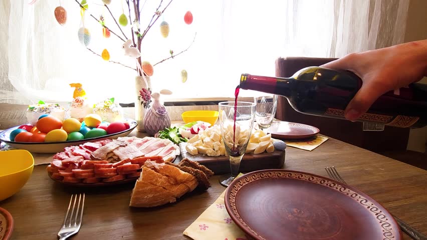 Easter - festive table with Easter cake, craft sausages, colored eggs, lard, cut vegetables and Cahors in glasses on a Ukrainian towel