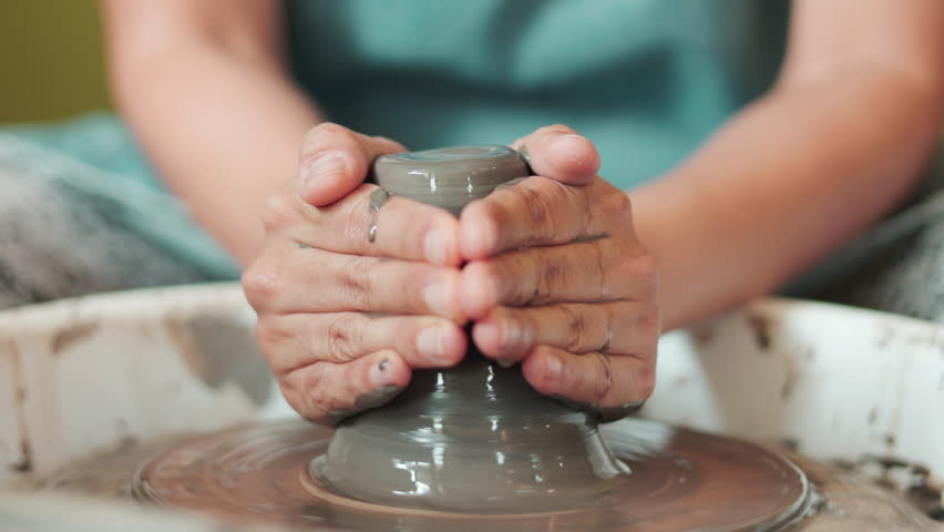 Close up of female hands shaping clay on pottery wheel in selective focus. Artistic handmade ceramic, learning pottery craft, creative process, traditional artisan skill, hobby and craftsmanship.