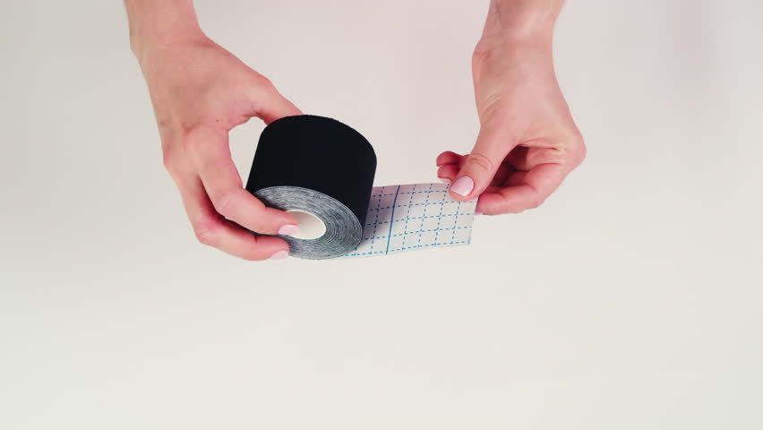 Kinesiology medical taping, doctor Physical therapist applying elastic surgical tape to patient body, treating injured knee young athlete.Post traumatic rehabilitation, sport physical therapy recovery