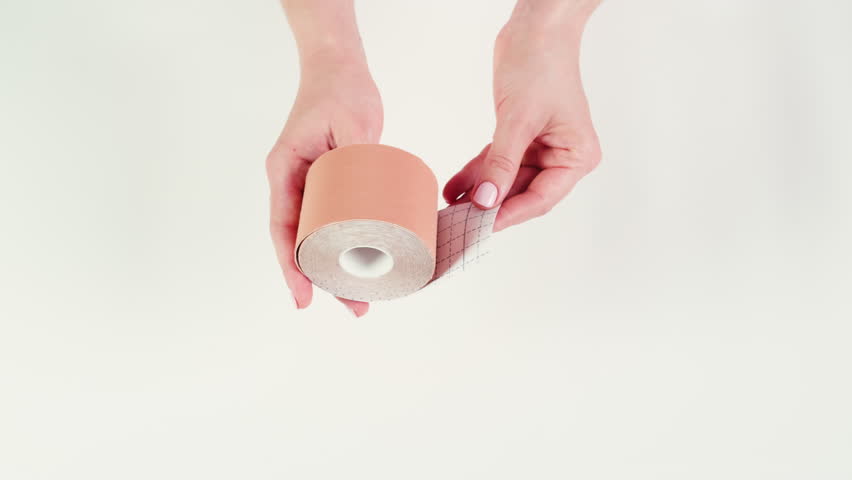 Kinesiology medical taping, doctor Physical therapist applying elastic surgical tape to patient body, treating injured knee young athlete.Post traumatic rehabilitation, sport physical therapy recovery