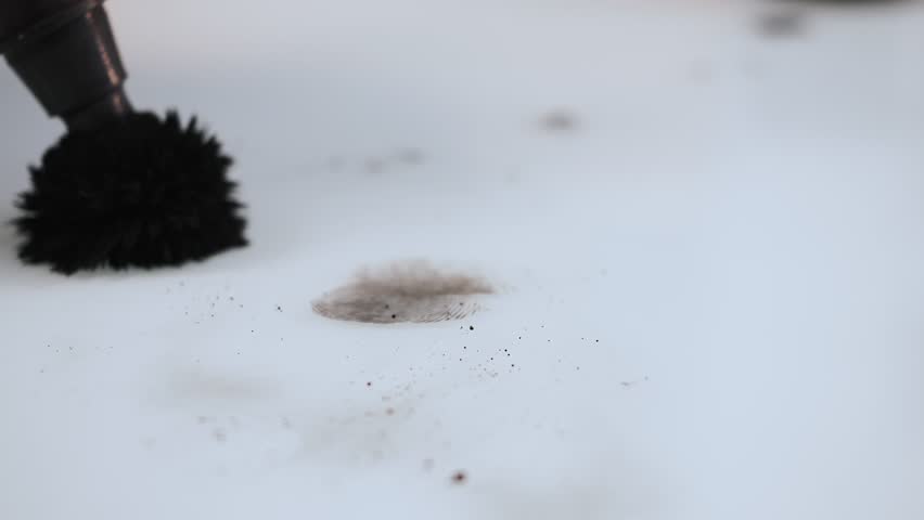 Forensic expert using a powder brush to reveal a clear fingerprint on a white surface during detailed indoor crime scene investigation.