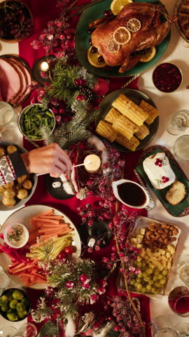 Friends giving presents to each other top view, celebrating new year, sitting at dining table. International young people making surprises. Diverse students during christmas party at home. 