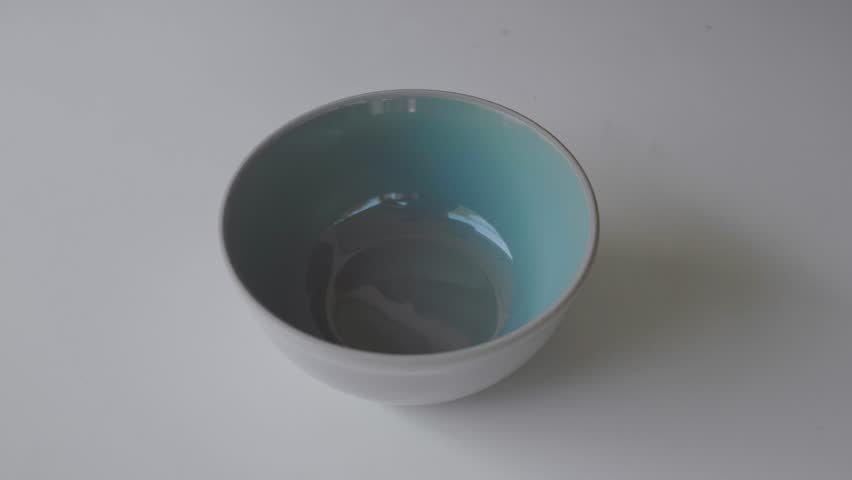 Mixed nuts are pouring into a bowl on a white background