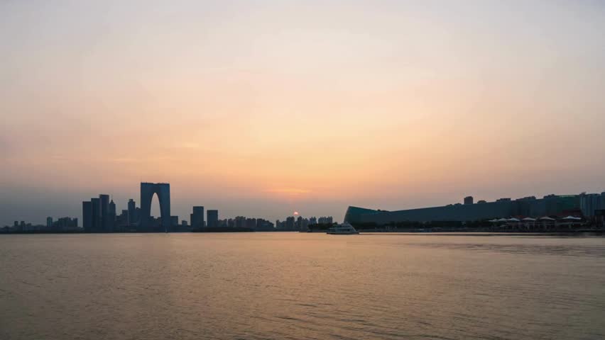 A stunning day-to-night time-lapse shows a modern city skyline lighting up after sunset, with colorful building lights reflecting beautifully across the calm lake.