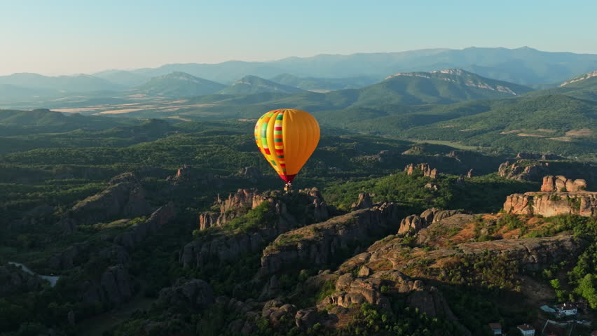 Aerial panorama Belogradchik Bulgaria colorful hot air balloon floating sunrise sky, surrounded by iconic Belogradchik Rocks, lush mountain scenery, city landscape summer tourism morning