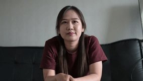 Young Asian woman influencer sitting on sofa at home during day while vlogging and having video call meeting - Powered by Shutterstock - Get 15% off with code: PIKWIZARD15