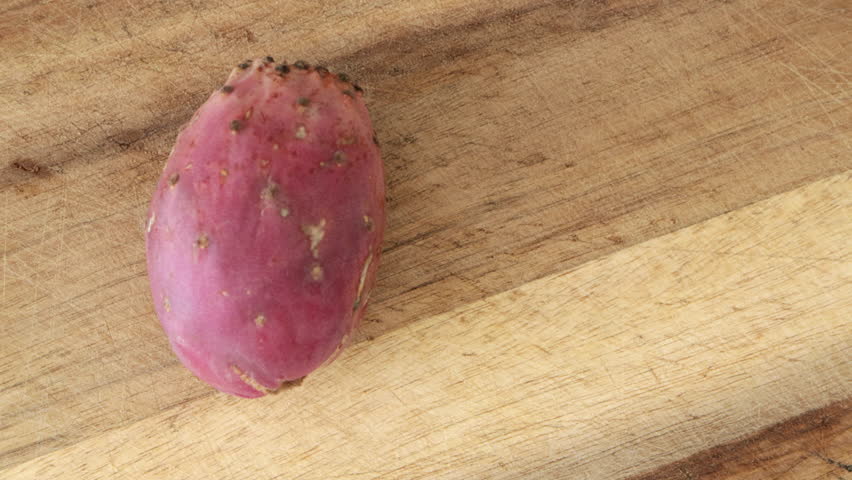 Cutting prickly pear cactus fruit opuntia on wooden board. Ficus indica close-up
