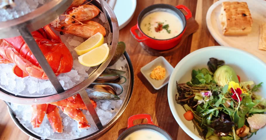 Fresh seafood platter with lobster, shrimp, mussels on ice, gourmet salad with avocado, vibrant ingredients, wooden table, fine dining experience.
