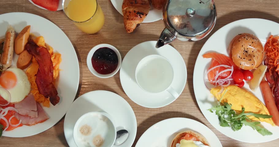 Delicious breakfast spread on table with pastries, coffee, juice, eggs, and smoked salmon. Fresh start to day with diverse, appetizing dishes.