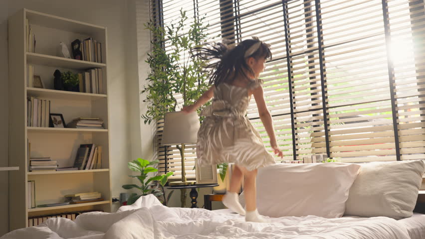 happiness cheerful Girl jumping on bed Adorable happy little girl in pajamas jumping on king-size bed in the morning.
