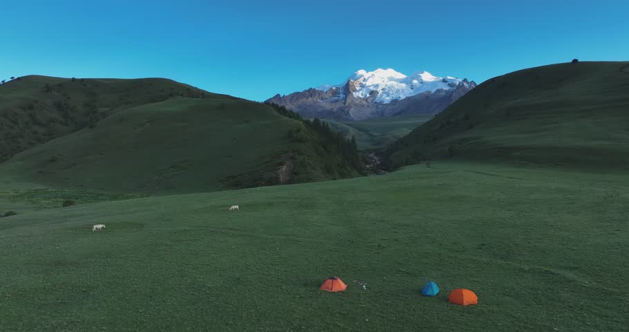 Aerial footage of have a camp with the beautiful high altitude snow capped mountains and grassland landscape in China