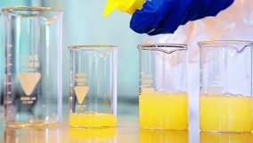 Scientist pouring orange fluid into beakers, gloves and safety lab gear in clean environment - Powered by Shutterstock - Get 15% off with code: PIKWIZARD15