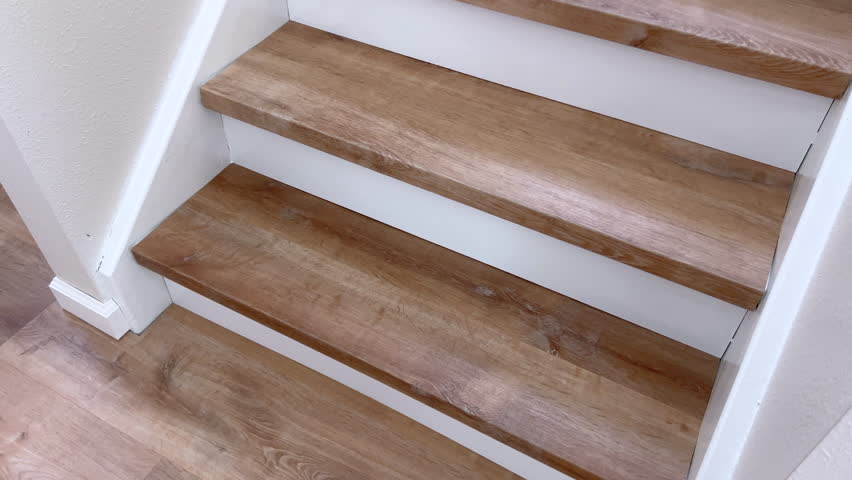 Clean residential staircase with brown wood steps and bright white trim. The view highlights the contrast between the two surfaces in natural daylight.