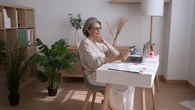 Professional senior businesswoman analyzing financial charts, working remotely on smartphone and laptop in home office workspace - Powered by Shutterstock - Get 15% off with code: PIKWIZARD15