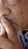 Vertical video: Senior African American man touching lips and gazing out window noticing movement. Contemplation, introspection, wisdom, serenity, mindfulness, thoughtfulness, vertical video - Powered by Shutterstock - Get 15% off with code: PIKWIZARD15