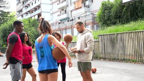 Coach holding clipboard standing near basketball players, providing strategic guidance and tactical instructions during outdoor team training session - Powered by Shutterstock - Get 15% off with code: PIKWIZARD15