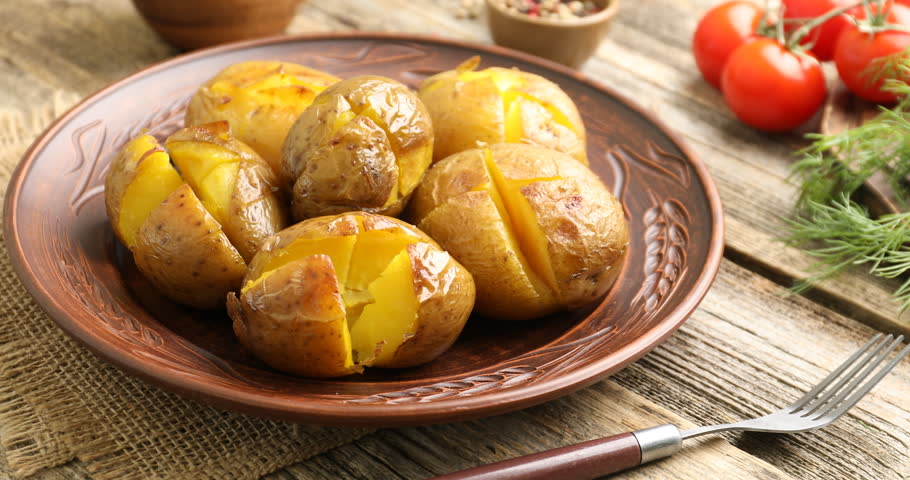 Tasty baked potatoes served at wooden table, closeup