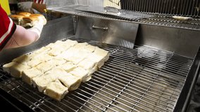 Gloved vendor toasts rows of buns on metal grill, indoor lighting, close-up, steady camera - Powered by Shutterstock - Get 15% off with code: PIKWIZARD15