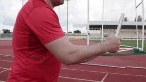 Runner practicing passing relay baton on athletics track - Powered by Shutterstock - Get 15% off with code: PIKWIZARD15