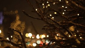 Festive christmas tree branches covered in snow, adorned with twinkling fairy lights, create a magical atmosphere against a backdrop of blurred city lights at night - Powered by Shutterstock - Get 15% off with code: PIKWIZARD15