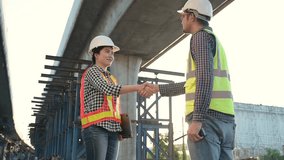 Male and female Asian engineers in safety helmets shaking hands at construction site under bridge with sunlight, symbolizing teamwork, trust, and successful collaboration. - Powered by Shutterstock - Get 15% off with code: PIKWIZARD15