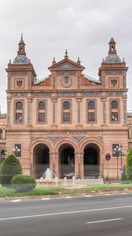 Facade of the General Captaincy of II Military Region in Seville, Spain. Headquarters of the Army Land Forces in Andalusia. Timelapse hyperlapse with traffic, cloudy sky and green trees.