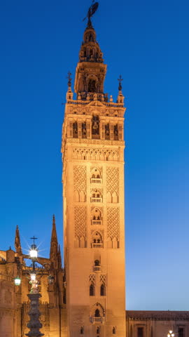 La Giralda and Seville Cathedral day to night transition timelapse, glowing with golden lights after sunset. The historic bell tower, gothic details and illuminated streets in Seville, Spain