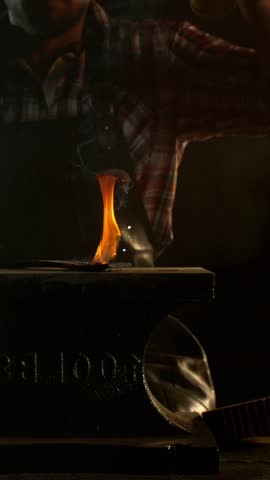 Close-up of blacksmith forging glowing hot iron on anvil with flying sparks. Super slow motion filmed on high-speed cinema camera at 1000 fps