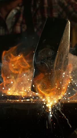 Close-up of blacksmith forging glowing hot iron on anvil with flying sparks. Super slow motion filmed on high-speed cinema camera at 1000 fps