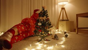 Woman in Santa Hat Sitting Near Decorated Mini Christmas Tree in Cozy Room with Gift Boxes and Glowing String Lights. - Powered by Shutterstock - Get 15% off with code: PIKWIZARD15