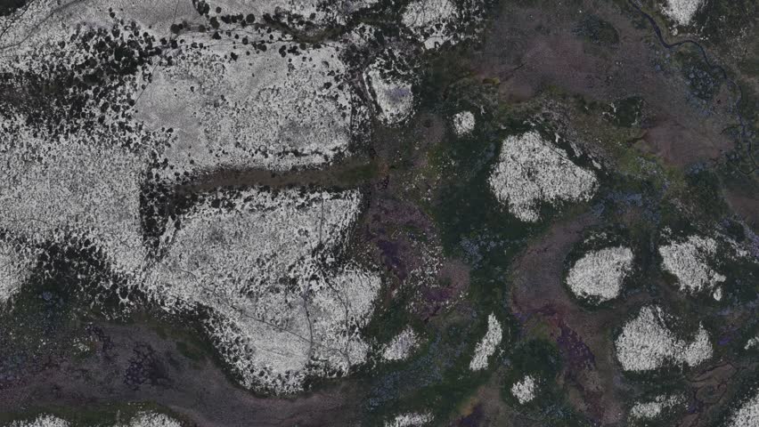 An aerial footage of the snow-dusted peaks and dark valleys weave wild textures across Rondane National Park, Norway
