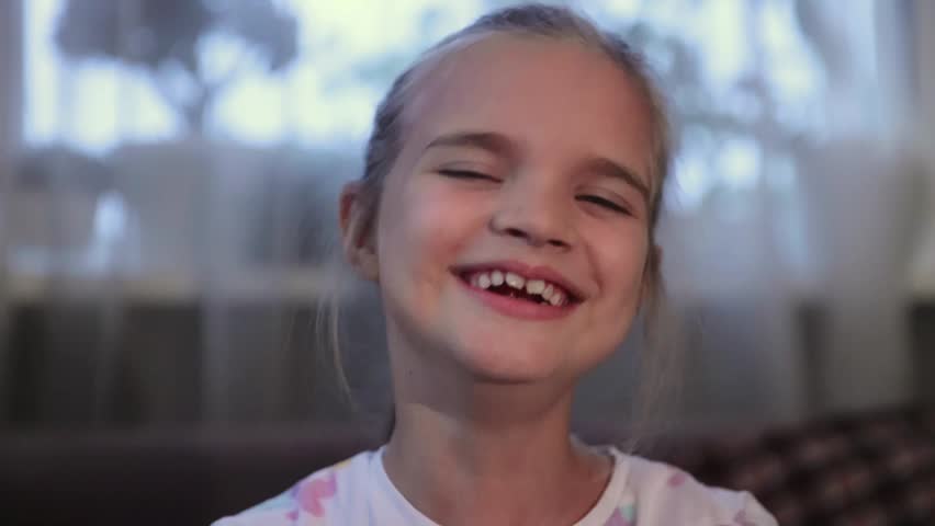 a portrait of a smiling little girl Looking at a camera in a room at home