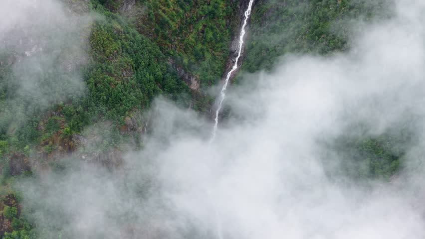 An aerial footage of Teigagrova River flowing through green mountain valley in Olden village in Vestland county, Norway on a foggy day