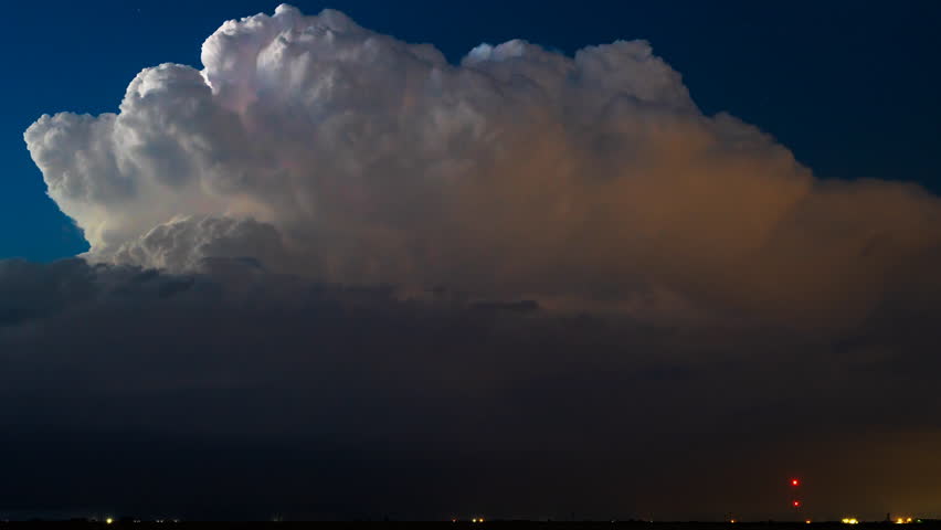 Time lapse captures lightning flashing within a towering storm cloud beneath a starry night sky, blending cosmic calm with intense electric energy in a stunning weather display