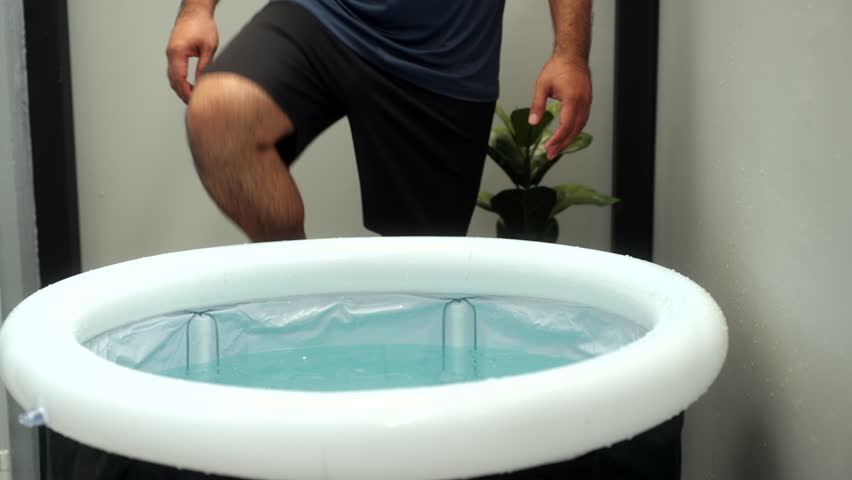 Close-up Man practices cold therapy and ice bathing in inflatable tub, using Wim Hof Method for wellness, meditation, fitness recovery, sports therapy. Wellness and healthy lifestyle.
