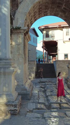 Vertical video of the Hadrian’s Gate in Kaleiçi, Antalya. A woman stands beneath the central arch, taking in the ancient Roman architecture