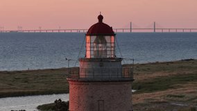 An aerial view of Falsterbo Lighthouse glows at dusk, overlooking the Baltic Sea, with the distant Oresund Bridge on the horizon, Sweden - Powered by Shutterstock - Get 15% off with code: PIKWIZARD15