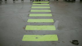 Fluorescent safety walkway markings on a polished concrete floor in an industrial facility, forming a bright guided path with reflective wet patches and strong perspective lines. - Powered by Shutterstock - Get 15% off with code: PIKWIZARD15