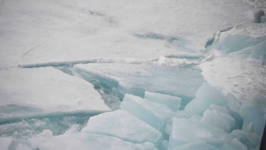 Shifting sea ice floes cracking and colliding on frigid polar waters, revealing jagged slabs, churning channels, and dynamic breakup of the frozen surface under seasonal pressure