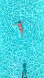 Top down view as a man dives into the pool while woman is laying on her back - Powered by Shutterstock - Get 15% off with code: PIKWIZARD15