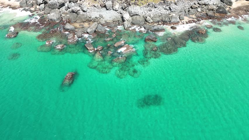 Aerial view of Fernando de Noronha coastline with waves crashing against rocky cliffs and lush tropical hills creating a stunning seascape.