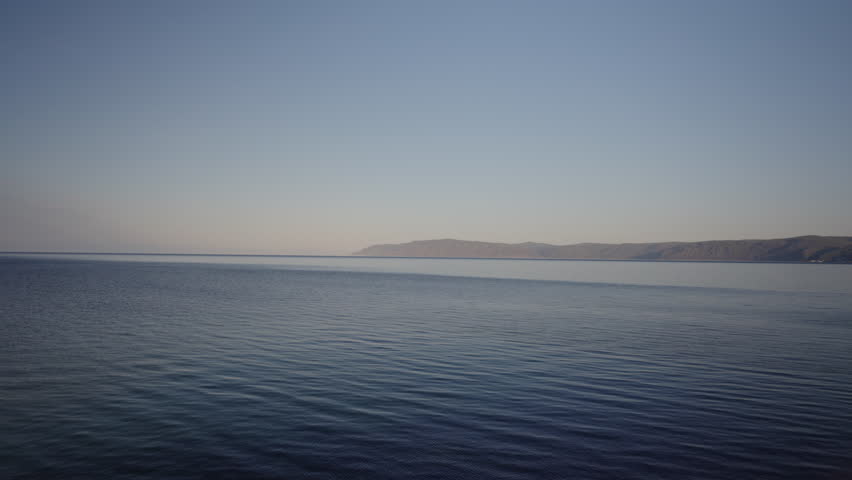 Idyllic view of vast expanse of lake Baikal stretches out to horizon, calm water mirroring clear blue sky above, creating serene scene of tranquility during boat trip, no people, nobody, slow motion.