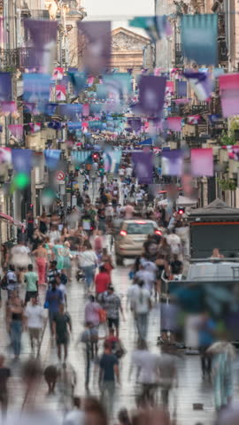 Tourists and locals walking and shopping in Rue Sainte-Catherine timelapse, Bordeaux, France. The longest pedestrian street in the country. Atmosphere of urban life. Colorful flags decorate the street