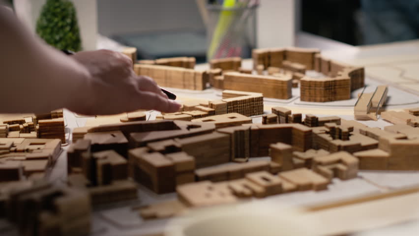 Close up of urban developers showing master plan for residential layout project, using 3D models on table to present idea of a smart city. Site preparation for infrastructure growth. Camera B.