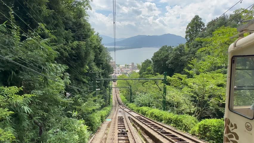Scenic view of Amanohashidate, a famous Japanese sandbar connecting Miyazu Bay and Kasamatsu Bay, featuring lush greenery, traditional boats, and breathtaking coastal scenery.