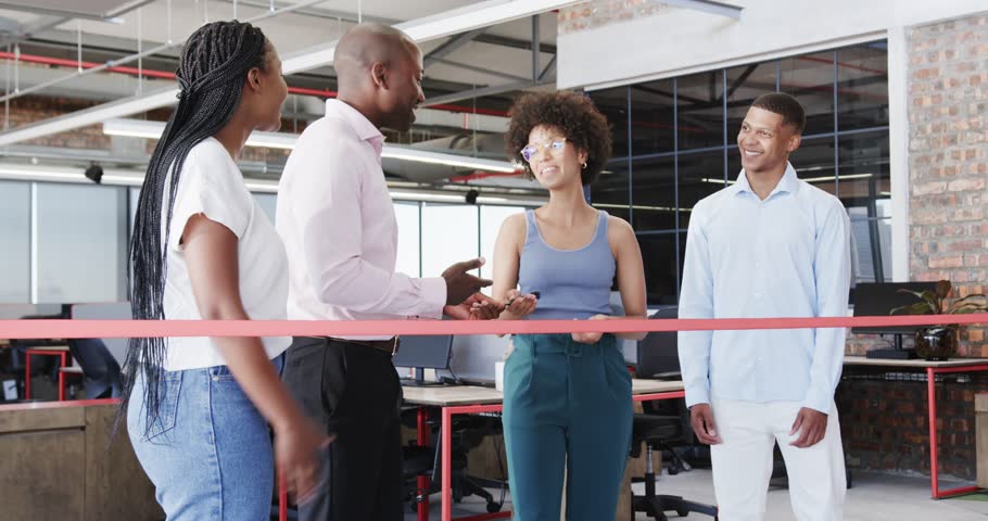 Diverse colleagues cutting red ribbon in modern office with scissors and joyful spirit. Celebration, teamwork, achievement, innovation, modern, professional, office