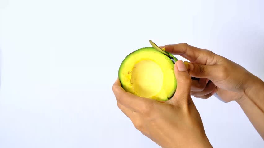 Young woman Peels Ripe Avocado, Preparing Healthy Vegetarian Breakfast, isolated white bcakground
