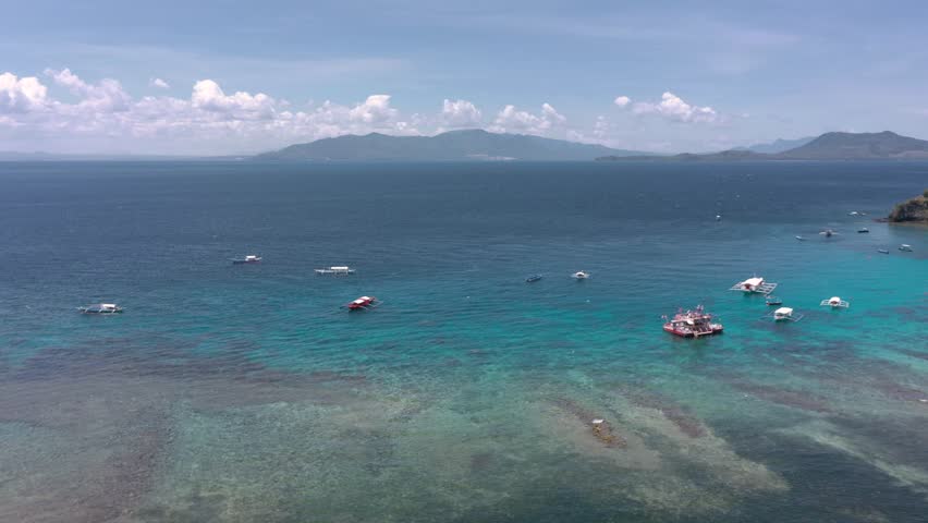 Drone flying over Puerto Galera and Sabang Bay with turquoise waters, boats, and diving schools, showcasing the tropical beauty of this famous Philippine destination.