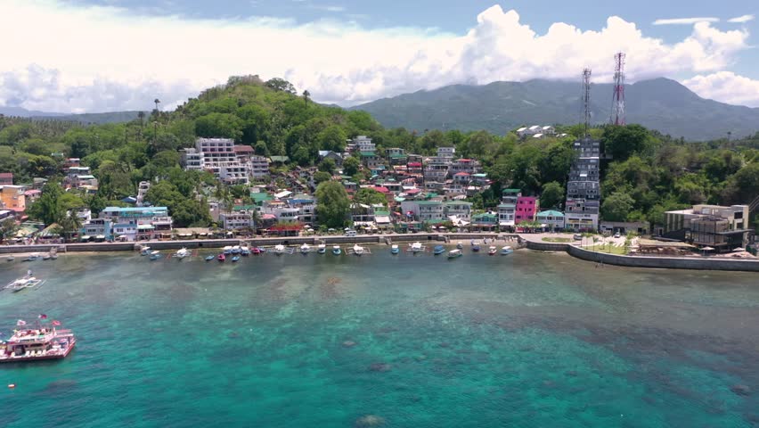 Awesome aerial of Puerto Galera and Sabang Bay with turquoise waters, boats, and diving schools, showcasing the tropical beauty of this famous Philippine destination.