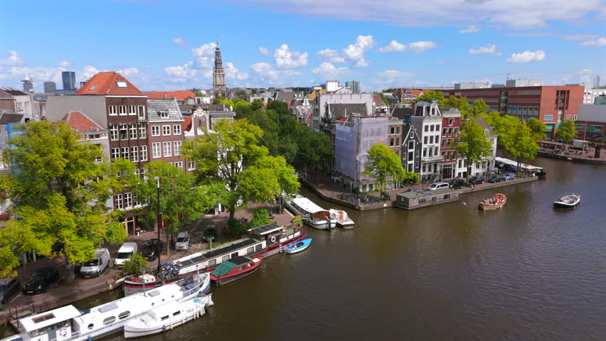 Stunning aerial view of the beautiful canals of Amsterdam, showcasing the vibrant greenery along the edges and the classic, historic Dutch architecture that defines the skyline
